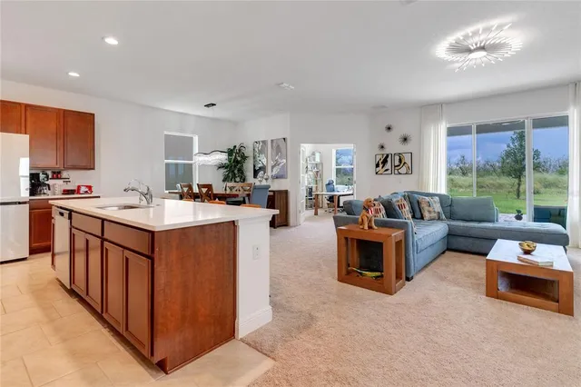 a living room with stainless steel appliances kitchen island granite countertop a sink a counter top space and living room view