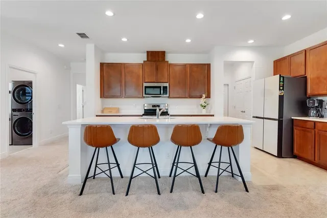 a kitchen with stainless steel appliances kitchen island granite countertop a table chairs sink and cabinets