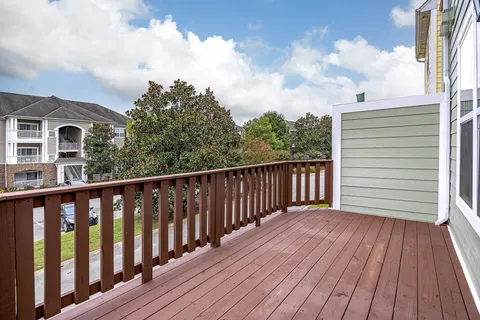 a balcony with wooden floor and trees in the background