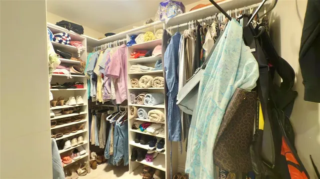 a view of walk in closet with clothes and shoes
