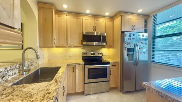 a kitchen with kitchen island granite countertop a stove a sink and a refrigerator