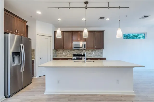 a large kitchen with kitchen island a large counter top stainless steel appliances and cabinets