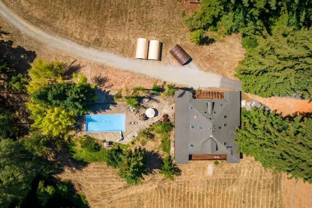 an aerial view of a house with a yard and large trees