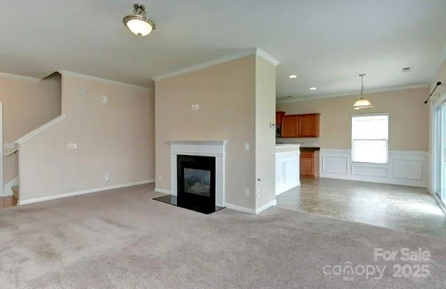 an empty room with kitchen view and a fireplace