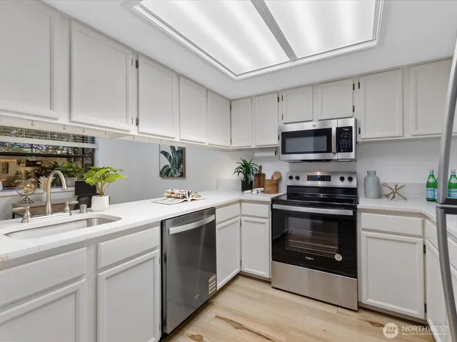 a kitchen with white cabinets stainless steel appliances and sink