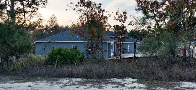 a view of a house with a small yard plants and large tree