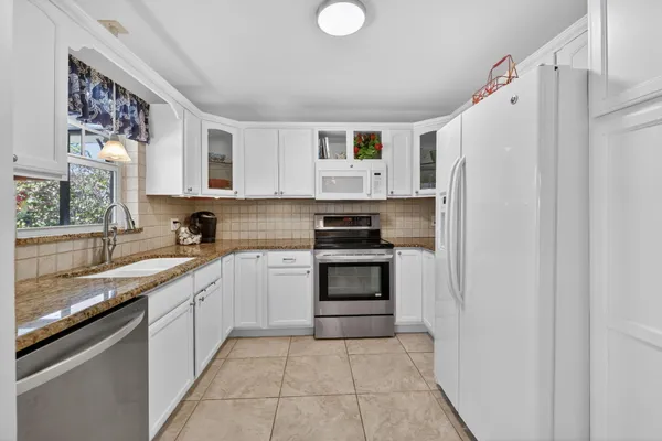 a kitchen with white cabinets and white appliances