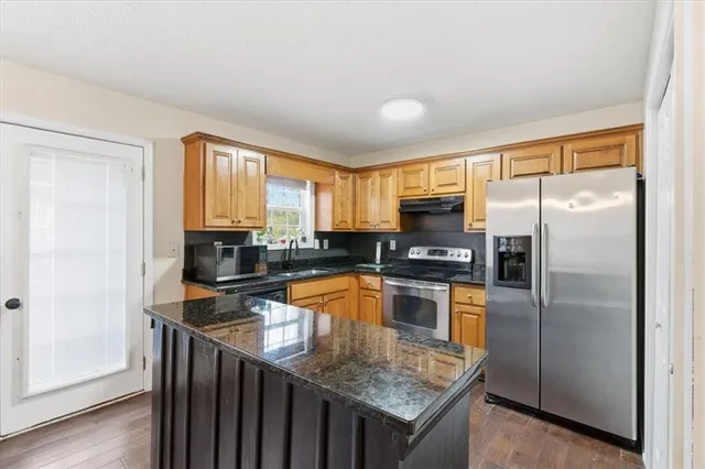 a kitchen with granite countertop a refrigerator a sink a stove and island