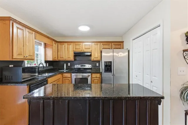 a kitchen with stainless steel appliances granite countertop a sink a stove and refrigerator