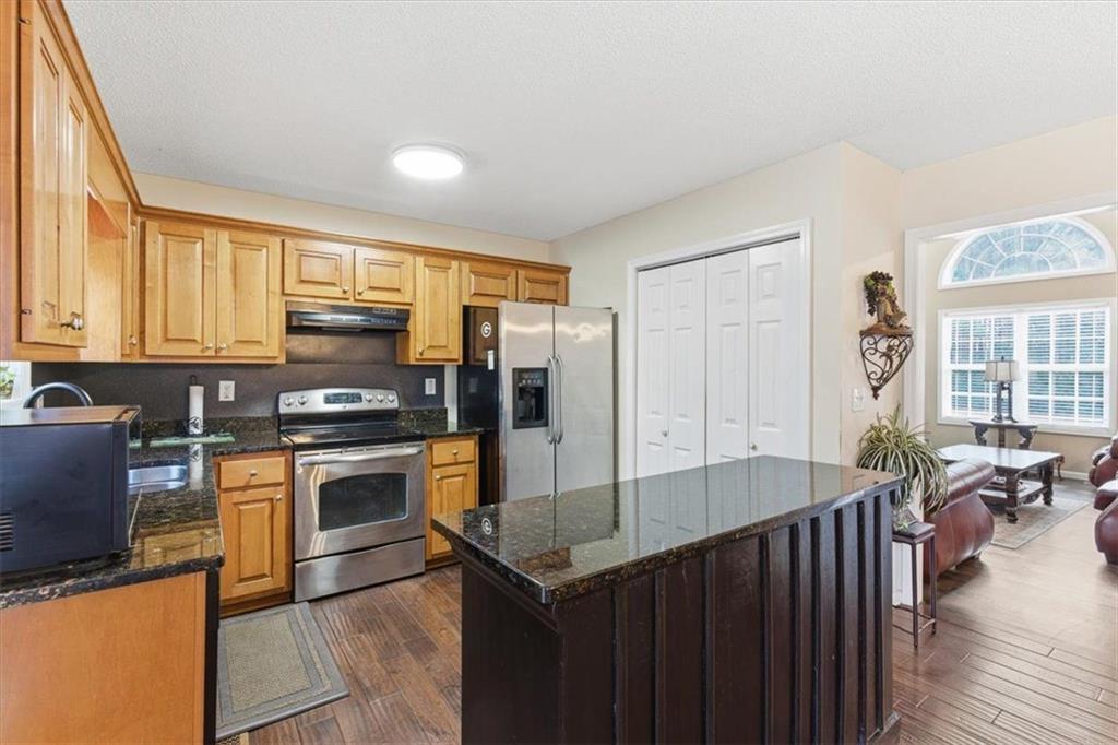 127 Prince Albert Court Southwest Calhoun, GA 30701 - Photo 14 of 50 a kitchen with stainless steel appliances granite countertop a stove top oven a sink dishwasher a dining table and chairs with wooden floor