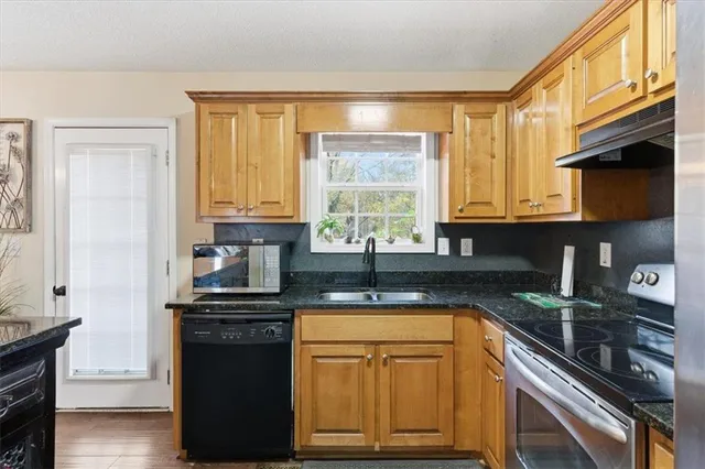 a kitchen with stainless steel appliances granite countertop a stove a sink and a microwave
