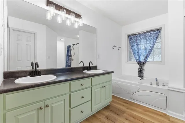 a bathroom with a granite countertop sink a mirror and a bathtub