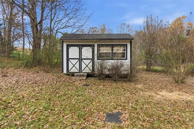a view of a house with a small yard and large tree