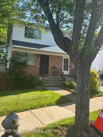 a view of a yard in front of a house with a large tree