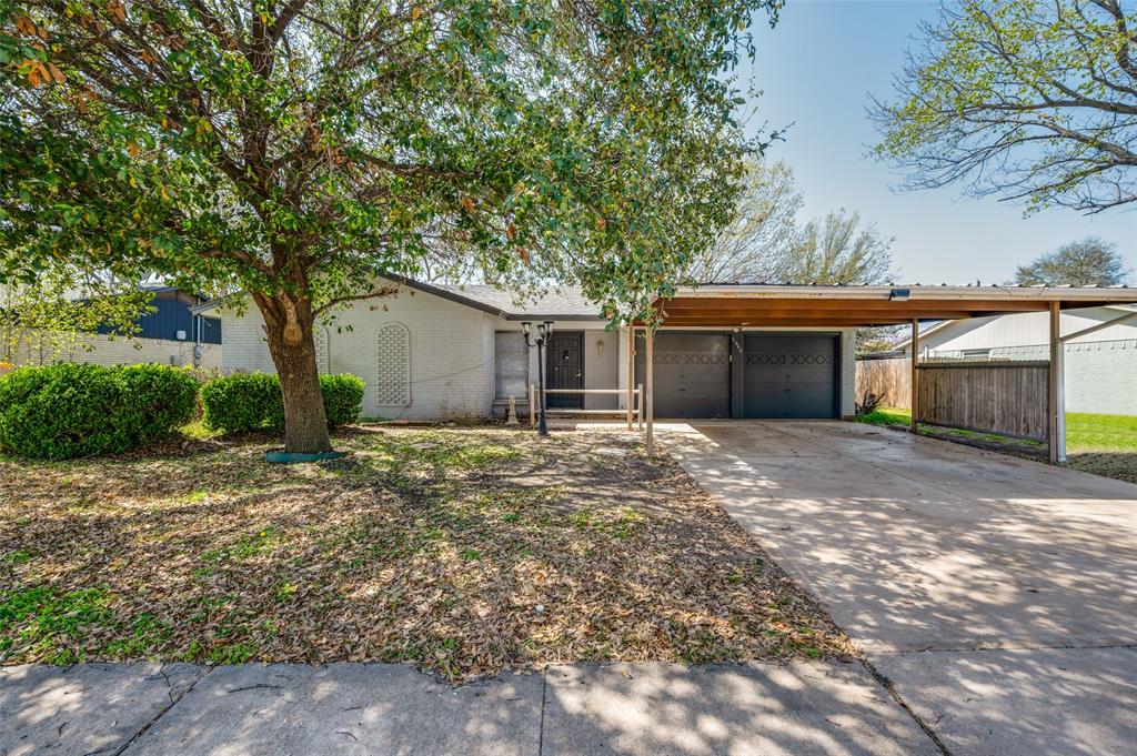 View of front of home featuring brick siding, an attached carport, an attached garage, and driveway