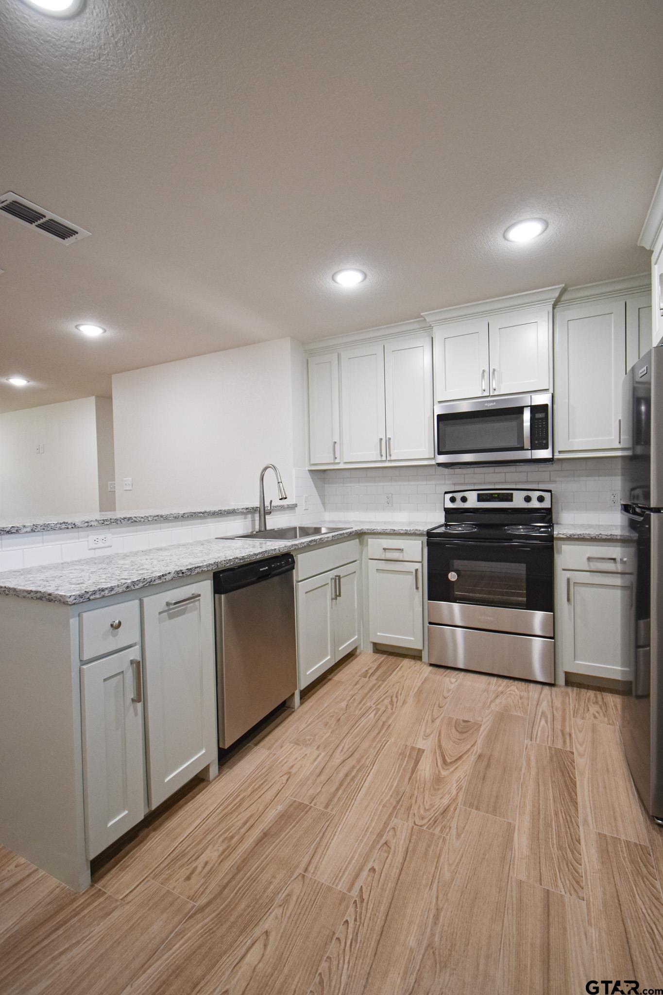 1417 East Earle Street Tyler, TX 75702 - Photo 12 of 31 a kitchen with granite countertop a sink and white stainless steel appliances