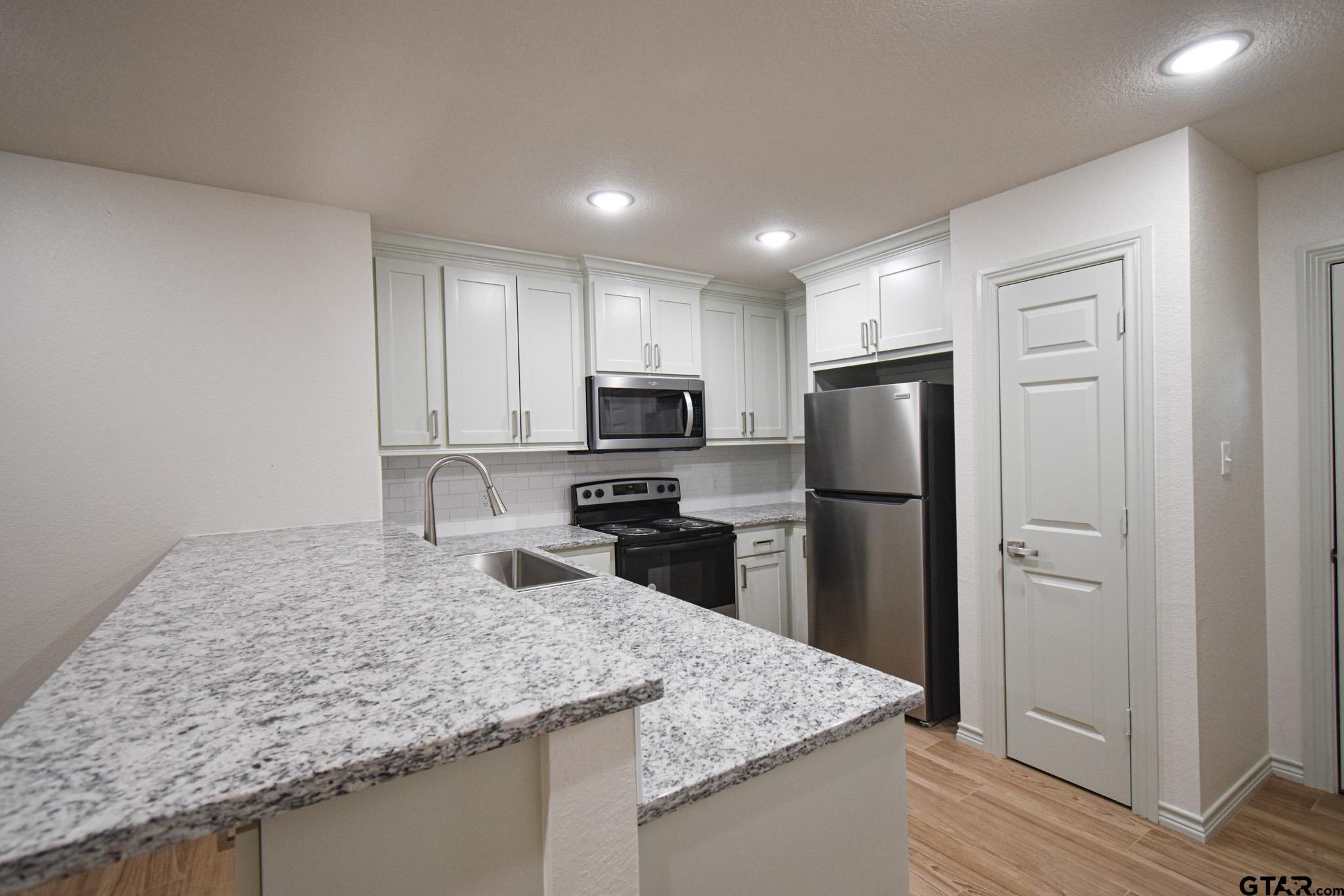 1417 East Earle Street Tyler, TX 75702 - Photo 13 of 31 a kitchen with a refrigerator a microwave and sink