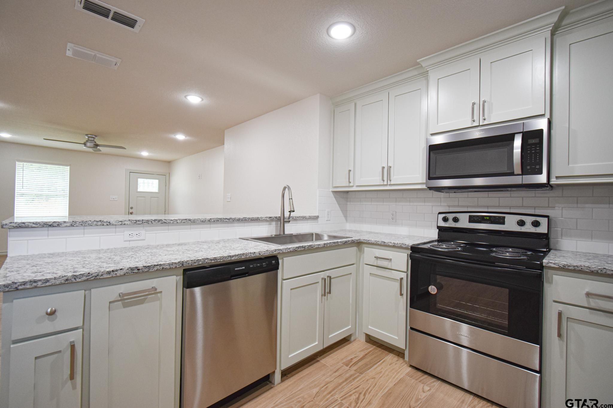 1417 East Earle Street Tyler, TX 75702 - Photo 14 of 31 a kitchen with stainless steel appliances granite countertop a sink and stove top oven