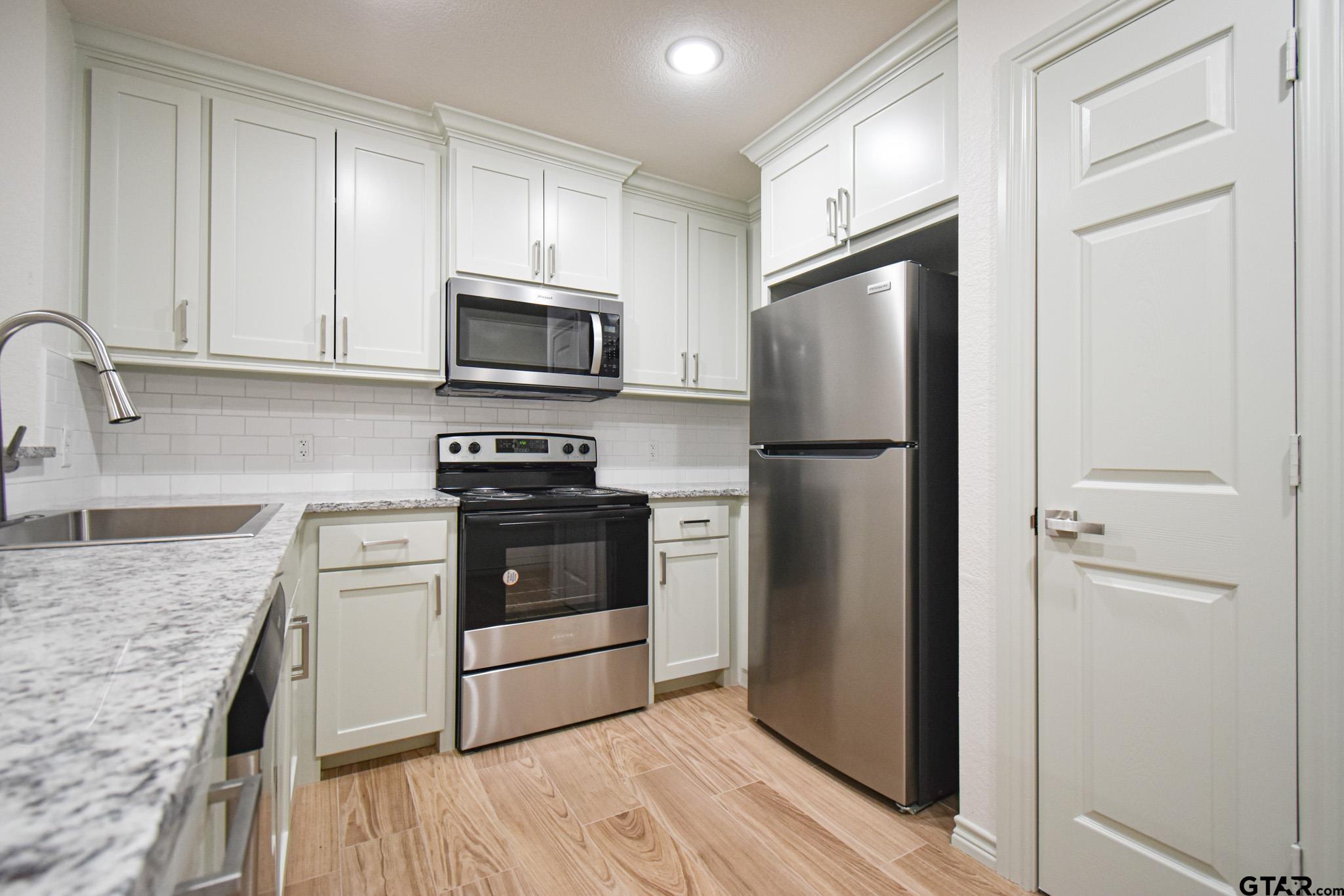 1417 East Earle Street Tyler, TX 75702 - Photo 15 of 31 a kitchen with granite countertop a refrigerator stove and microwave
