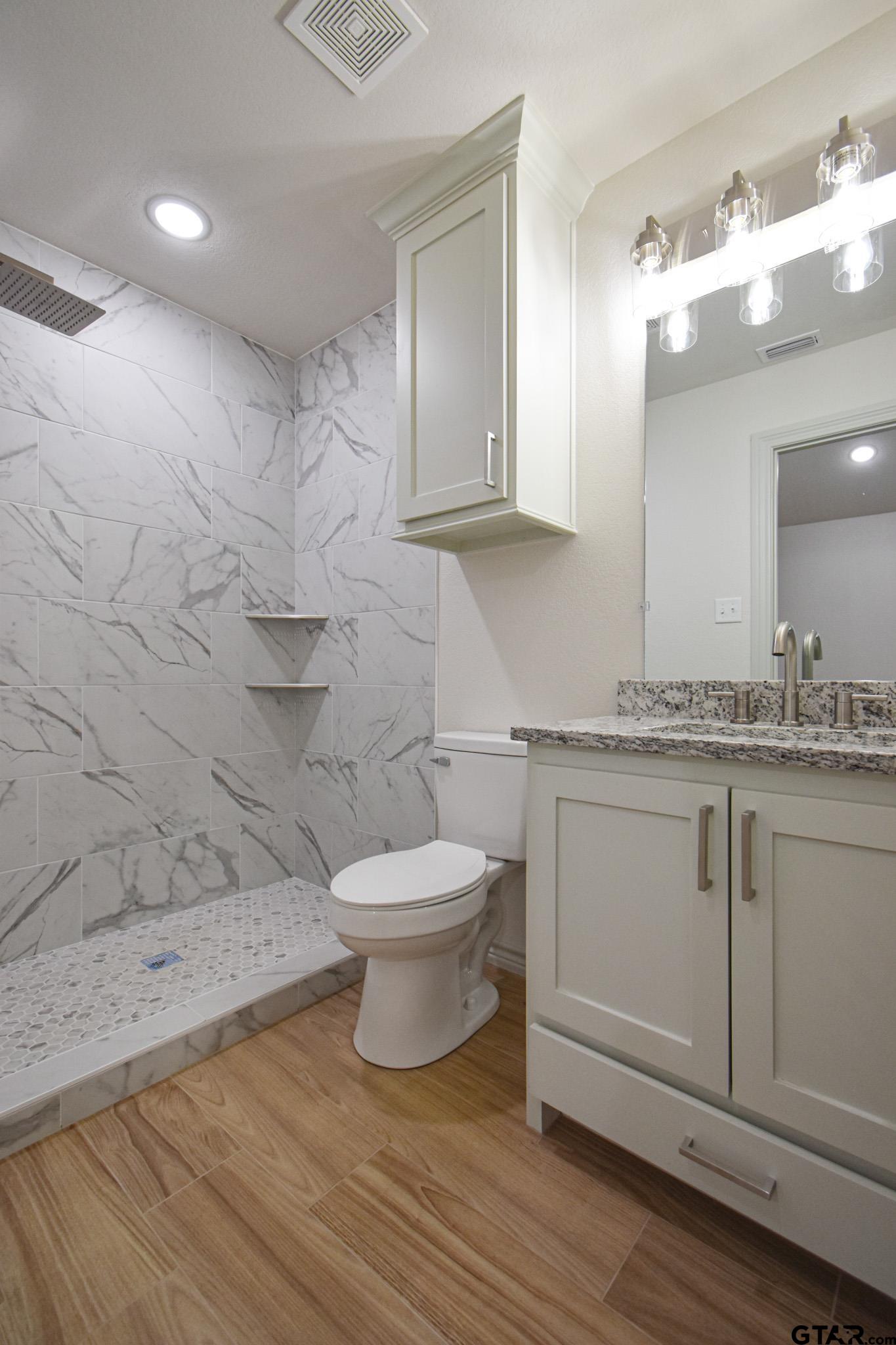 1417 East Earle Street Tyler, TX 75702 - Photo 23 of 31 a bathroom with a sink a toilet and mirror