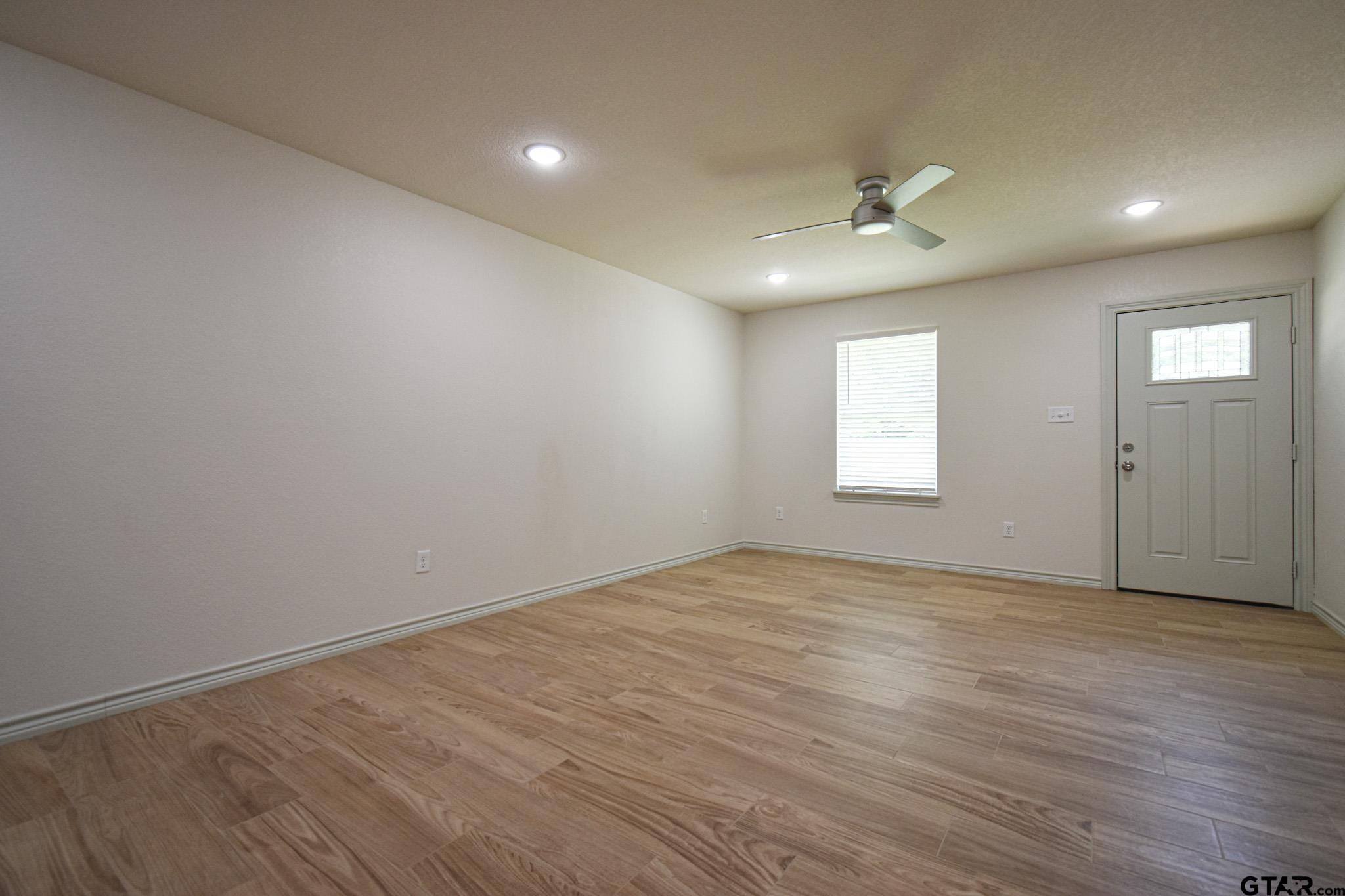 1417 East Earle Street Tyler, TX 75702 - Photo 10 of 31 an empty room with wooden floor ceiling fan and windows