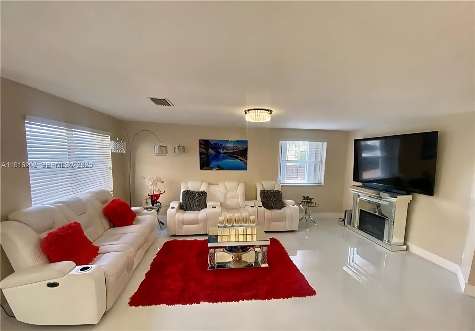 8568 Southwest 211th Terrace, Unit 8576 Cutler Bay, FL 33189 - Photo 3 of 12 a living room with furniture a flat screen tv and a couch