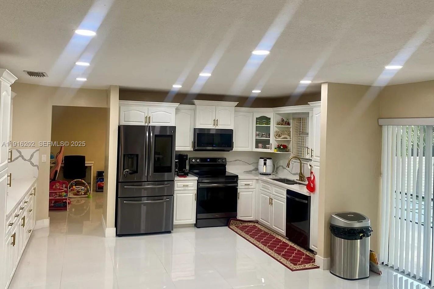 8568 Southwest 211th Terrace, Unit 8576 Cutler Bay, FL 33189 - Photo 9 of 12 a kitchen with stainless steel appliances granite countertop a refrigerator and a stove top oven