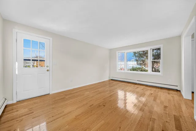 a view of an empty room with a window and wooden floor