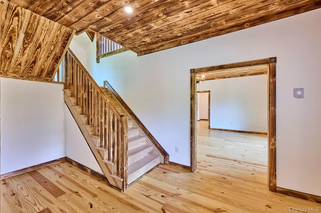 a view of an empty room with wooden floor fireplace and a window