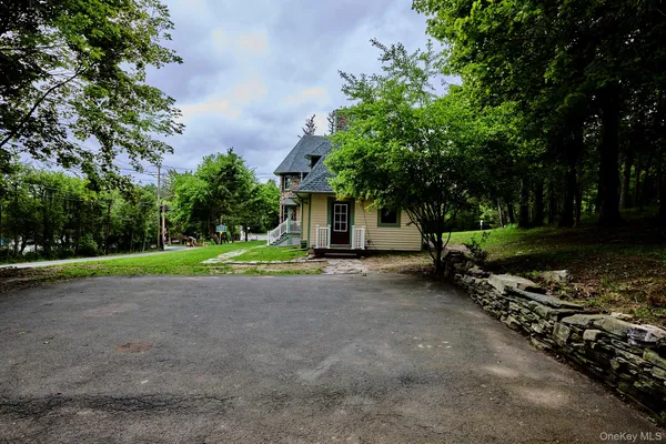 a view of a house with large trees and a small yard