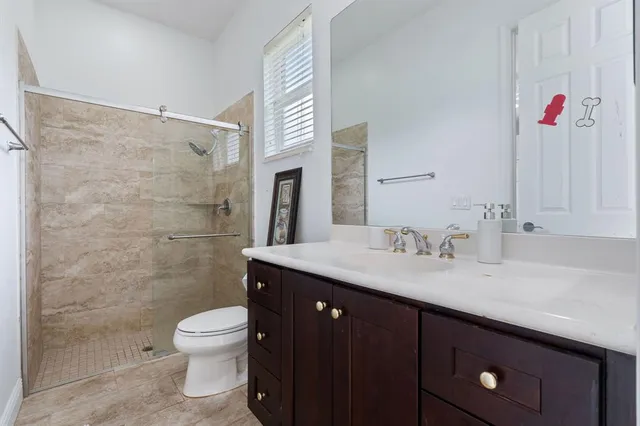 a bathroom with a granite countertop sink a toilet and a shower