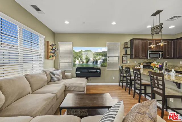 a living room with furniture kitchen view and a large window