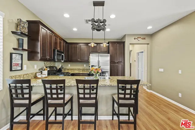 a kitchen with stainless steel appliances granite countertop a dining table chairs sink and cabinets