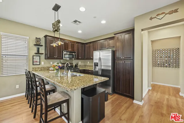 a kitchen with stainless steel appliances granite countertop a sink refrigerator and cabinets
