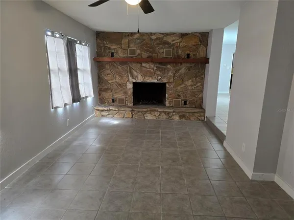 a view of an empty room with fireplace and a window