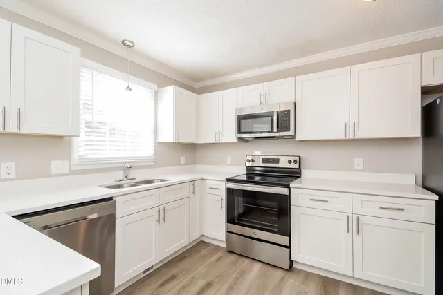 a kitchen with white cabinets appliances and a sink