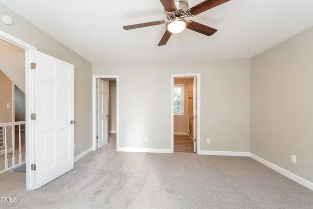 a view of an empty room and chandelier fan