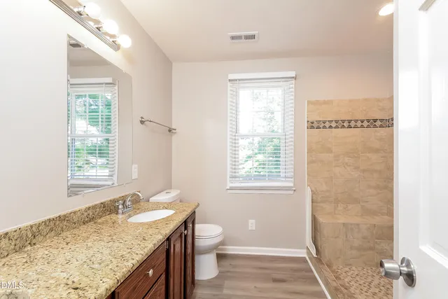 a bathroom with a granite countertop sink a toilet and a shower