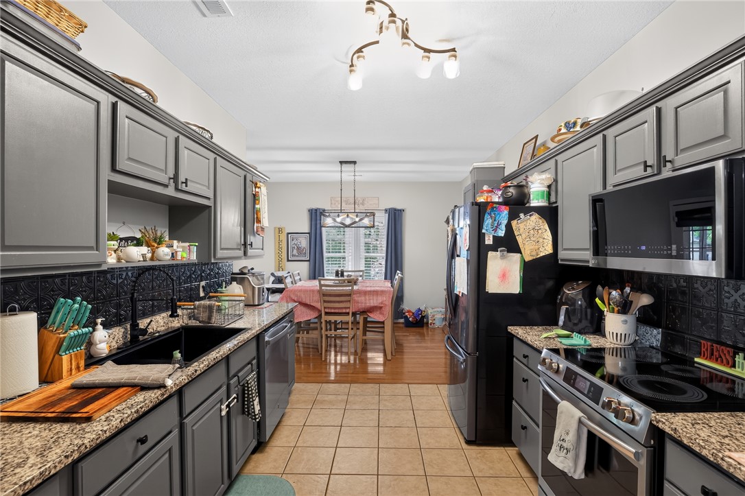144 Elliott Circle Anderson, SC 29621 - Photo 11 of 30 A well-appointed kitchen features ample gray cabinetry and elegant granite counters, opening to a sun-drenched dining area.
