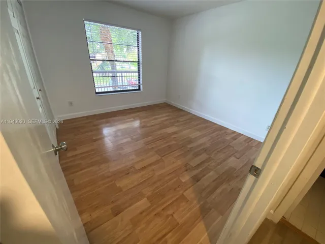 an empty room with wooden floor closet and windows