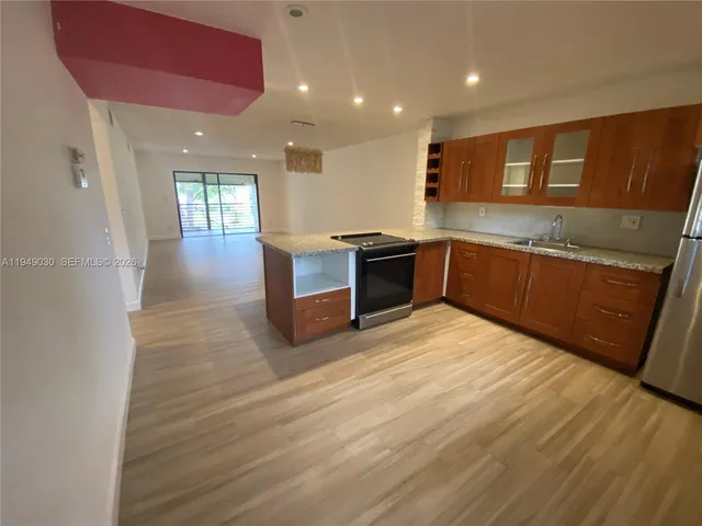 a large kitchen with stainless steel appliances granite countertop a large counter top a sink and a refrigerator