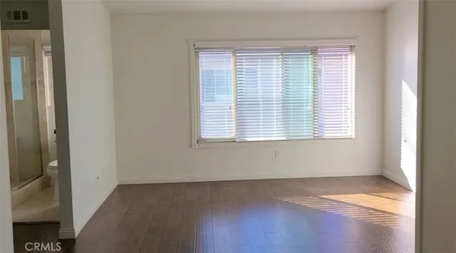 a view of an empty room with wooden floor and a window