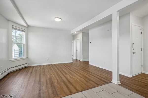 a view of an empty room with wooden floor and a window