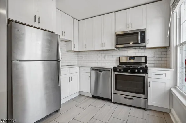 a kitchen with stainless steel appliances white cabinets white stove a microwave and a refrigerator