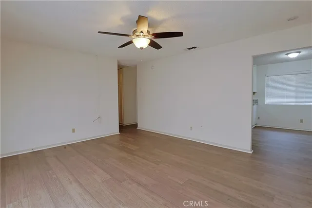 an empty room with wooden floor fan and windows