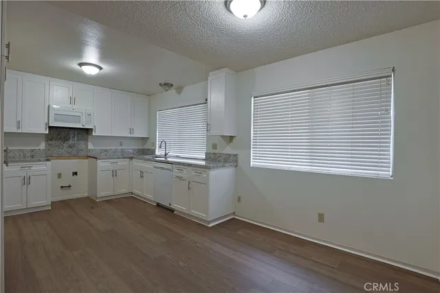 a kitchen with granite countertop white cabinets and white appliances