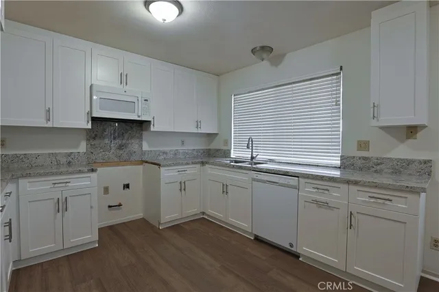 a kitchen with granite countertop white cabinets white appliances with a sink and dishwasher