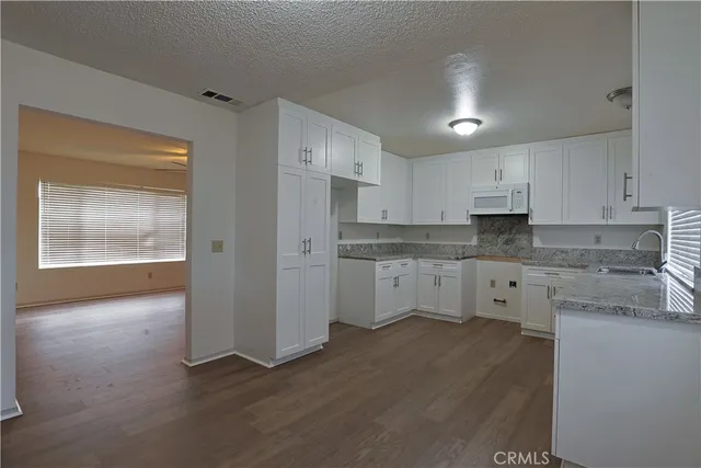 a kitchen with granite countertop white cabinets and white appliances