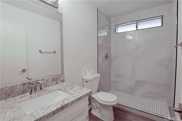 a bathroom with a granite countertop sink a toilet and shower