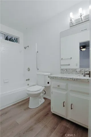 a bathroom with a granite countertop toilet a sink and a mirror